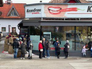 Menschenansammlung vor einem Küchenstudio mit rege Beteiligung und Dekoration.